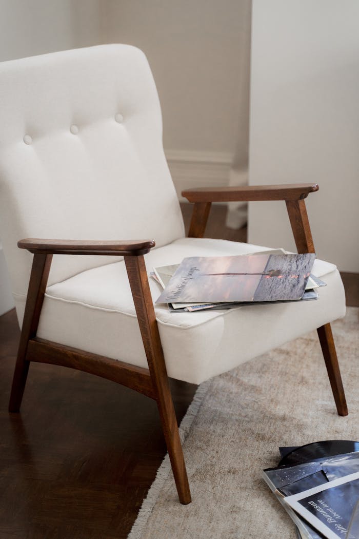 our-services-1 Elegant mid-century modern armchair with magazines on a plush carpet in a warm living room setting.