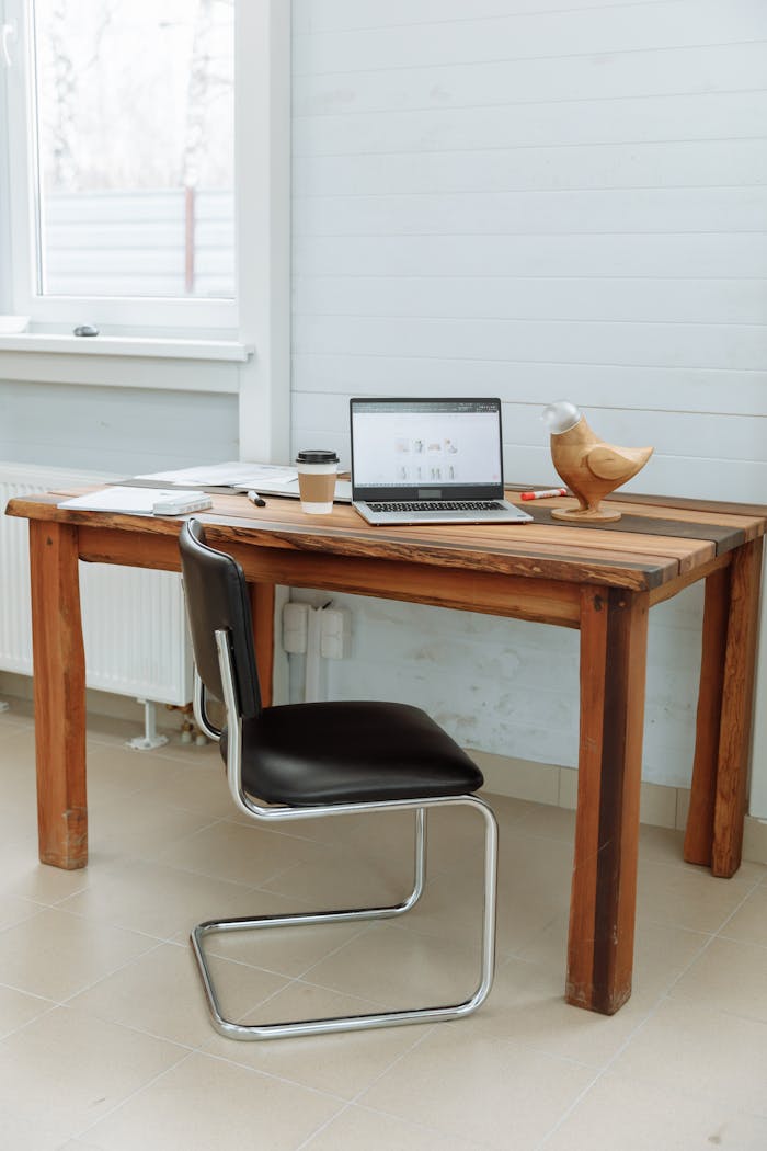 hero-img-01 Simple office desk setup with a laptop, coffee cup, and wooden bird figurine.